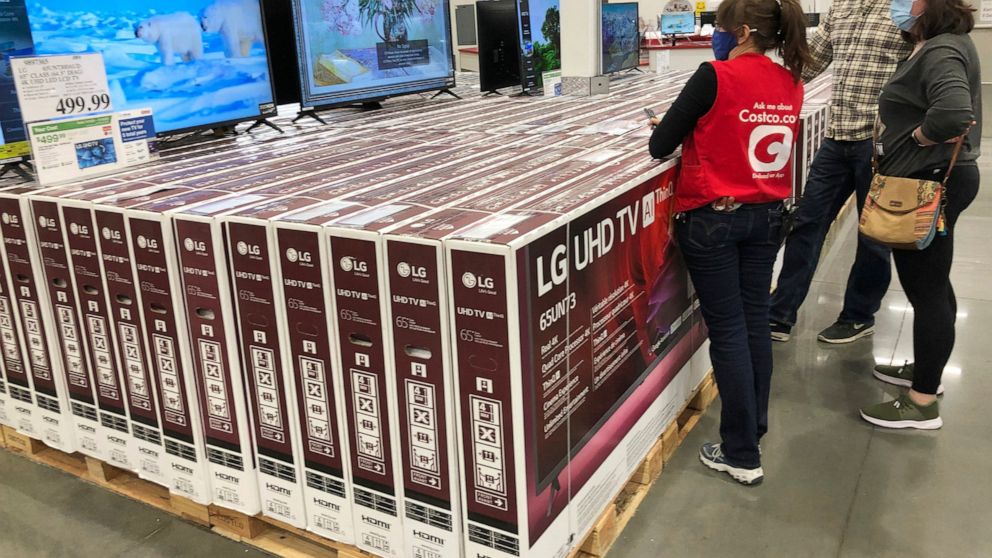 A sales associate helps customers as they consider the purchase of a big-screen television at a Costco warehouse on Wednesday, Nov. 18, 2020, in Sheridan, Colo. U.S. consumer confidence fell to a reading of 96.1 in November as rising coronavirus case