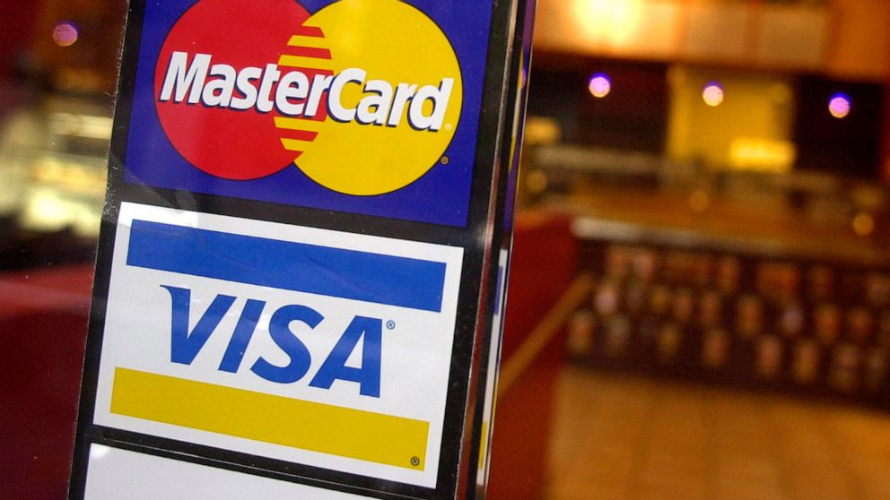 FILE - This April 22, 2005, file photo, shows logos for MasterCard and Visa credit cards at the entrance of a New York coffee shop. Mastercard and Visa are suspending their operations in Russia, the companies said Saturday, March 5, 2022, in the late