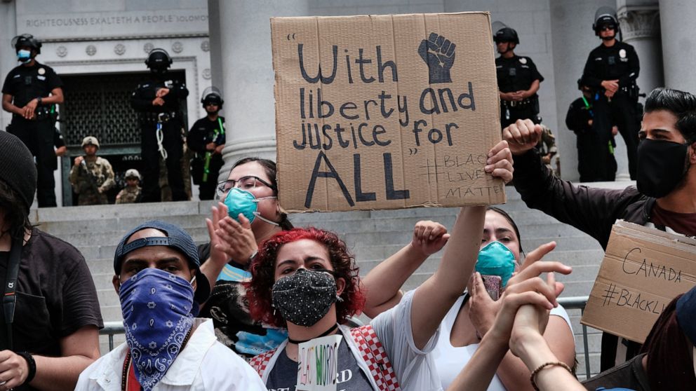 FILE - Police and National Guard block Los Angeles City Hall as protesters hold a signs and chant during a Black Lives Matter protest in Los Angeles, on June 2, 2020, over the death of George Floyd. Responding to what the MacArthur Foundation called 