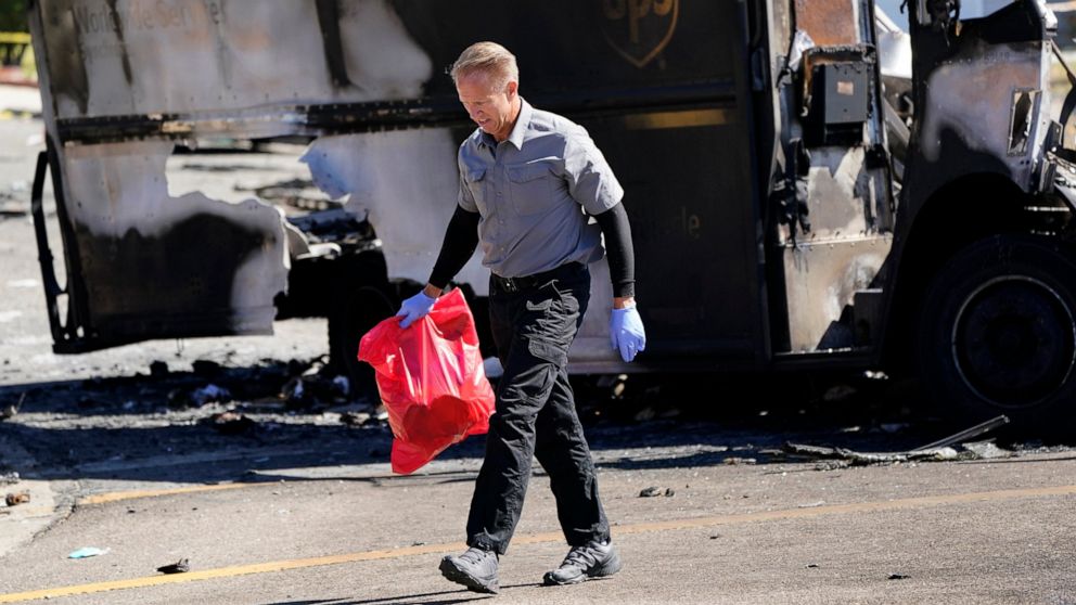 An official from the San Diego County medical examiners office carries items from the site of a plane crash Tuesday, Oct. 12, 2021, in Santee, Calif. Recordings indicate the pilot of a twin-engine plane nose-dived into this San Diego suburb Monday de