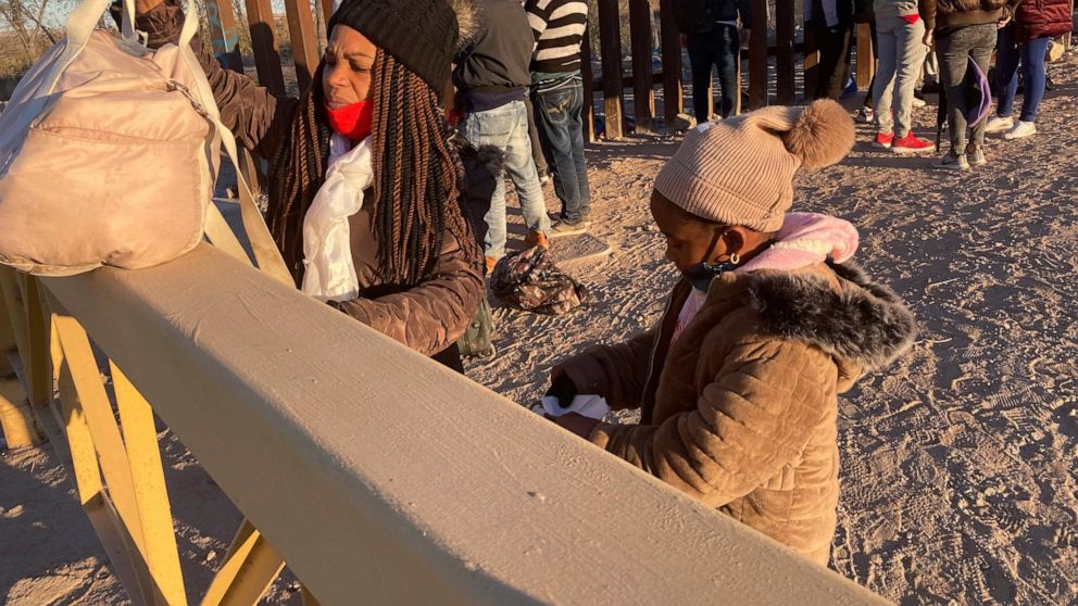 A Cuban woman and her daughter wait in line to be escorted to a Border Patrol van for processing in Yuma, Ariz., Sunday, Feb. 6, 2022, hoping to remain in the United States to seek asylum. For nationalities that don't need a visa, Mexico is often the