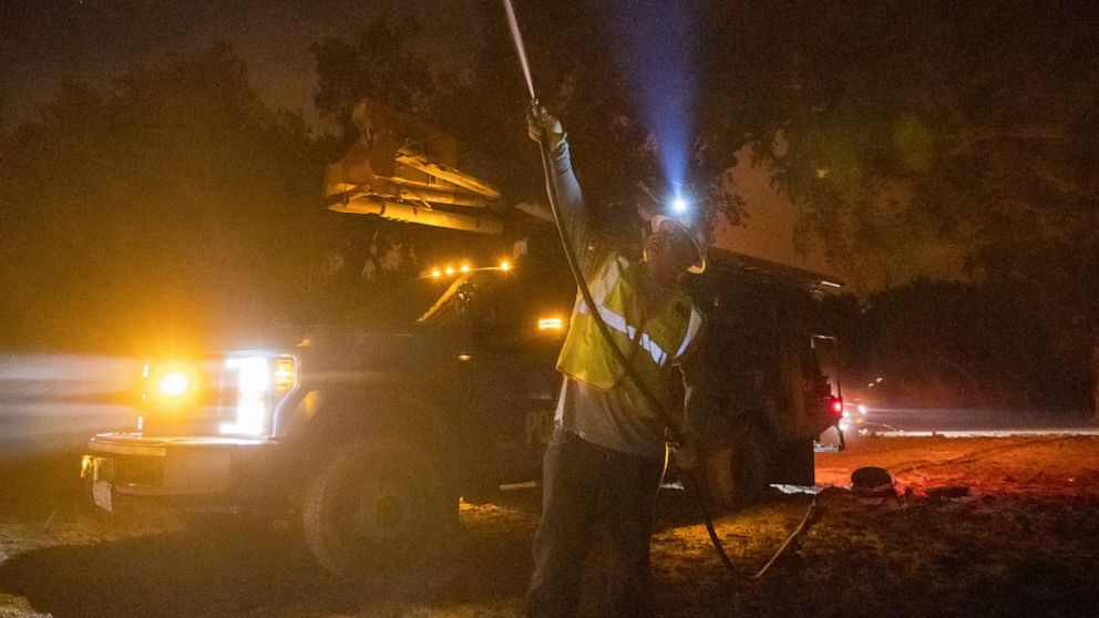 FILE - In this Sept. 28, 2020, file photo, a Pacific Gas & Electric employee sprays water on a burning telephone pole at the Zogg Fire near Ono, Calif. Officials say the wildfire that killed four people and destroyed more than 200 buildings last year