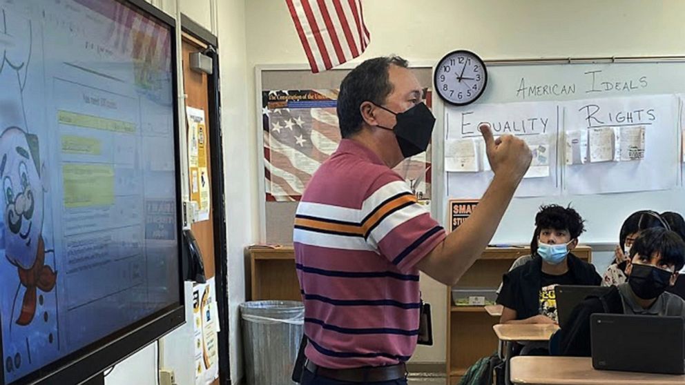 This photo shows Daniel Santos, a middle school history teacher during class, in Houston, in November, 2021. Teachers around the U.S. are confronting classrooms where as many as half of students are absent. That's because they have been exposed to CO