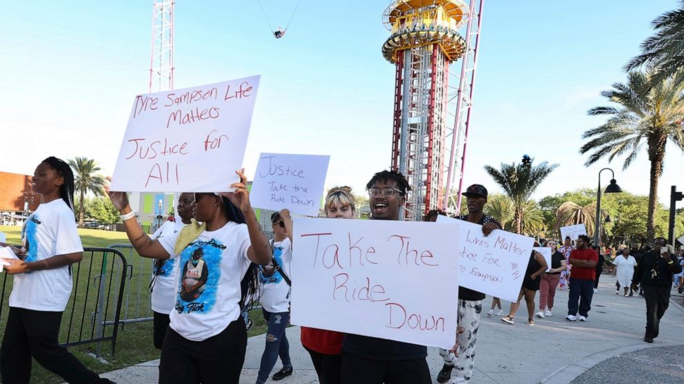 FILE - Family and supporters of Tyre Sampson march and hold signs outside the Orlando Free Fall drop tower ride at ICON Park in Orlando on March 29, 2022. A towering amusement ride in central Florida's tourism district where Tyre, 14, died when he fe