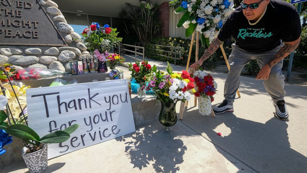 A man places flowers at a memorial Wednesday, June 15, 2022, outside El Monte City Hall for two police officers who were shot and killed Tuesday, at a motel in El Monte, Calif. The two police officers were killed in a shootout while investigating a p