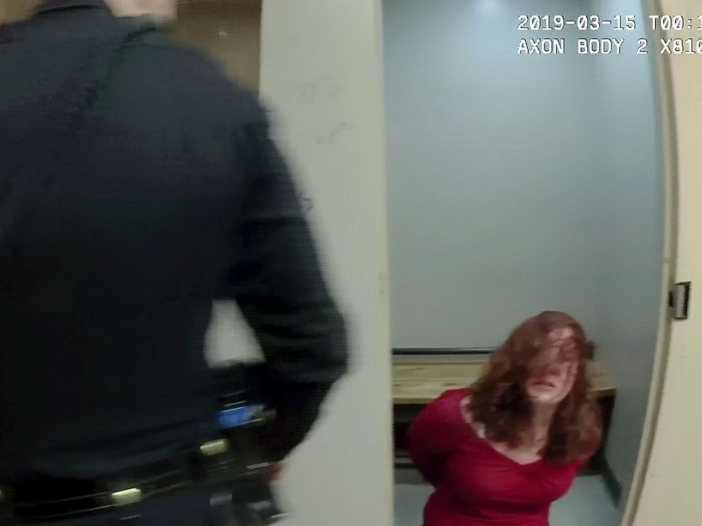 In this March 14, 2019, image taken from body camera video released by the St. Albans Police Department Amy Connelly kneels on the floor of a holding cell at the police station in St. Albans, Vt. The police chief said he has changed the use-of-force 