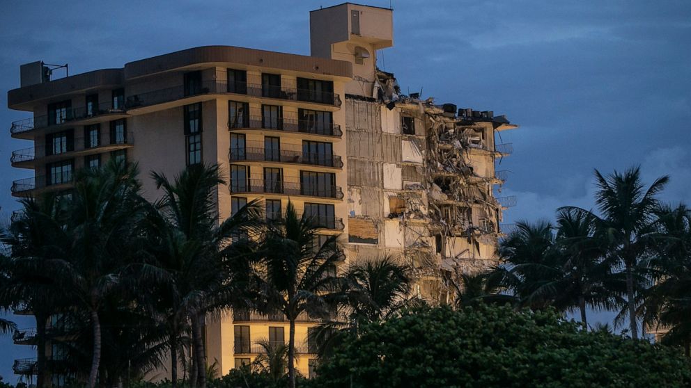 FILE - In this June 30, 2021, file photo, light shines on the Champlain Towers South as search and rescue teams continue looking for survivors of the partially collapsed residential building in Surfside, Fla. Dozens of people escaped with their lives