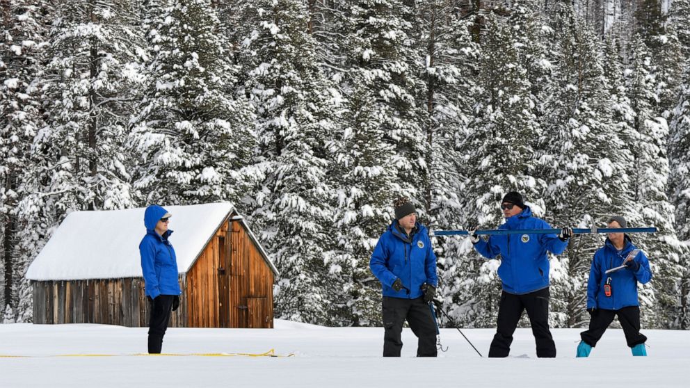 In this photo provided by the California Department of Water Resources, forecasting chief Sean de Guzman, second from right, and engineers work the measurement phase of the first media snow survey of the season at Phillips Station in the Sierra Nevad