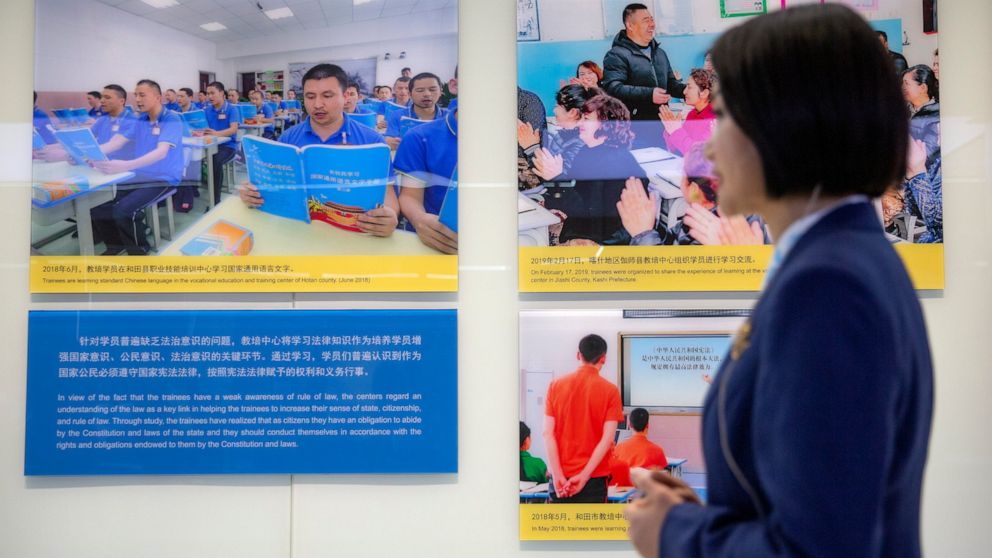 A tour guide stands near a display showing images of people at locations described as vocational training centers in southern Xinjiang at the Exhibition of the Fight Against Terrorism and Extremism in Urumqi in western China's Xinjiang Uyghur Autonom