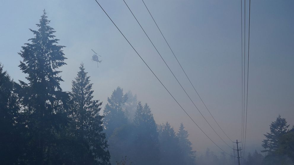 A water-drop helicopter flies Wednesday, Sept. 9, 2020, near a wildfire burning in Bonney Lake, Wash., south of Seattle. (AP Photo/Ted S. Warren, Pool)