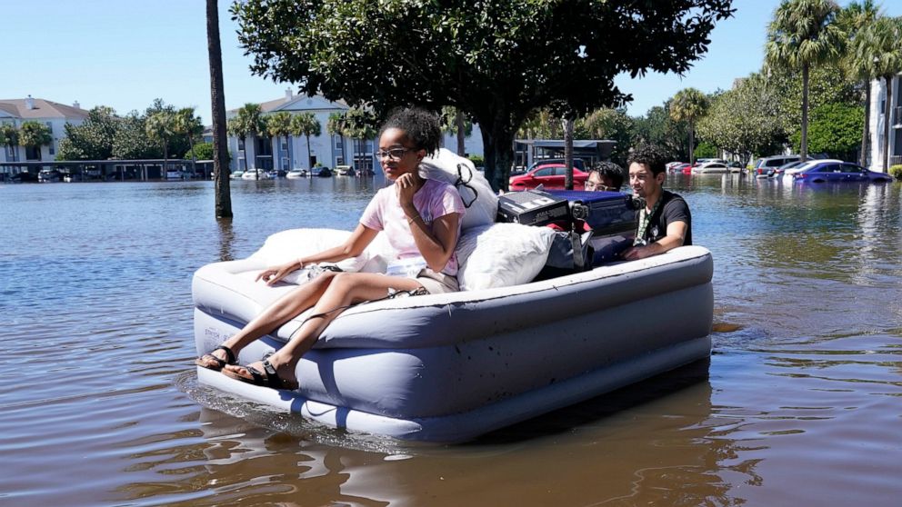 University of Central Florida students use an inflatable mattress as they evacuate an apartment complex near the campus that was totally flooded by rain from Hurricane Ian, Friday, Sept. 30, 2022, in Orlando, Fla. AP Photo/John Raoux)