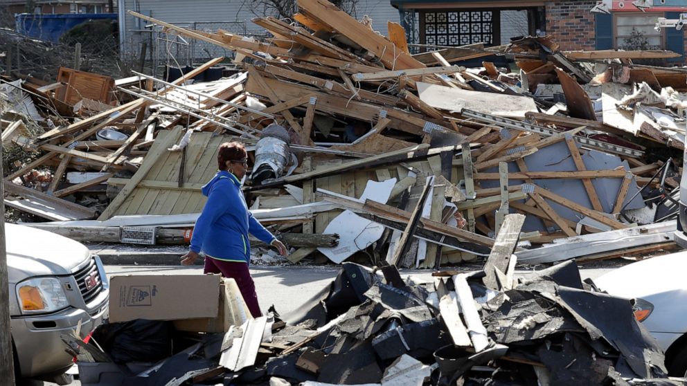 A woman walks down a street lined with debris Friday, March 6, 2020, in Nashville, Tenn. Residents and businesses face a huge cleanup effort after tornadoes hit the state Tuesday. (AP Photo/Mark Humphrey)