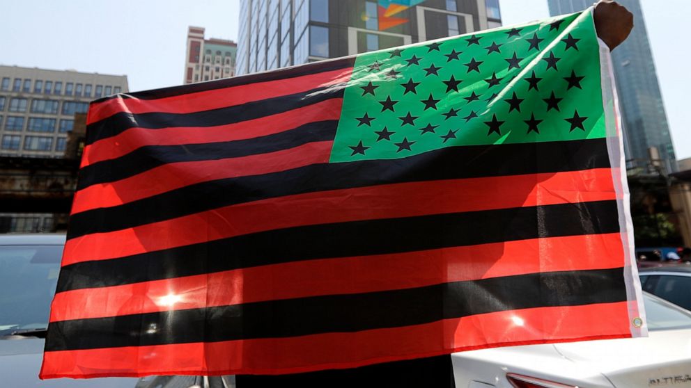 FILE - A man holds an African-American flag during a demonstration in Chicago on June 19, 2020, to mark Juneteenth, the holiday celebrating the day in 1865 that enslaved black people in Galveston, Texas, learned they had been freed from bondage, more