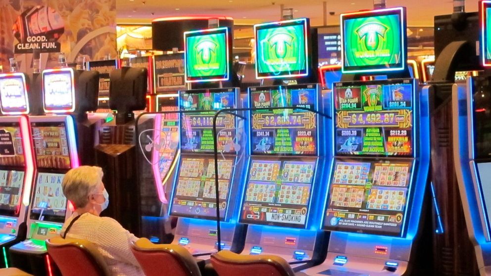 In this May 3, 2021 photo a woman plays a slot machine while wearing a mask in the Hard Rock casino in Atlantic City, N.J. On May 11 the American Gaming Association released statistics showing that the U.S. commercial casino industry matched its best