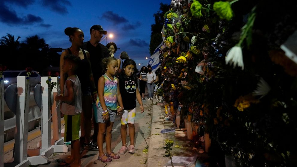 FILE - Well-wishers visit a makeshift memorial for the victims of the Champlain Towers South condo building collapse, as they gather for a multi-faith vigil near the site where the building once stood on July 15, 2021, in Surfside, Fla. Friday marks 