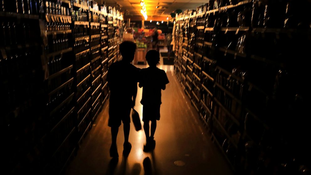 FILE - In this Oct. 23, 2019, file photo, Elijah Carter 11, left, and Robert Haralson, 12, help shop for their parents in a darkened Olivers Supermarket during a blackout in the Rincon Valley community in Santa Rosa, Calif. When Pacific Gas & Electri