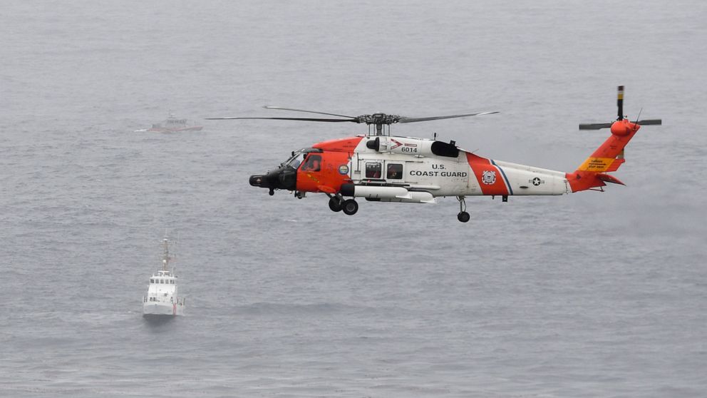 A U.S. Coast Guard helicopter flies over boats searching the area where a boat capsized just off the San Diego coast Sunday, May 2, 2021, in San Diego. (AP Photo/Denis Poroy)