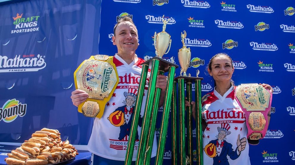 Winners Joey Chestnut and Michelle Lesco pose with their championship belts and trophies at the Nathan's Famous Fourth of July International Hot Dog-Eating Contest in Coney Island's Maimonides Park on Sunday, July 4, 2021, in Brooklyn, New York. (AP 