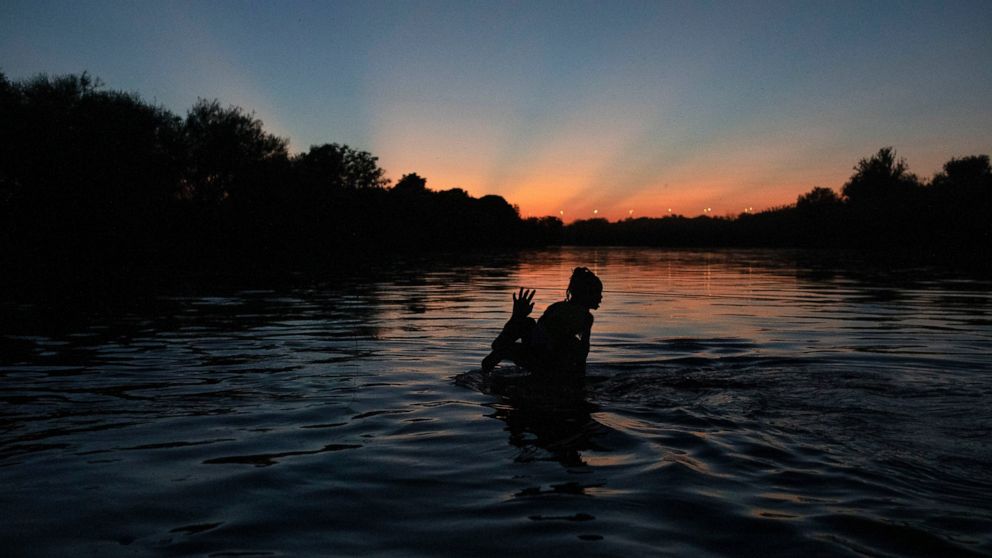 Migrants wade across the Rio Grande from Del Rio, Texas, to Ciudad Acuña, Mexico, Sunday, Sept. 19, 2021. The U.S. is flying Haitians camped in a Texas border town back to their homeland and blocking others from crossing the border from Mexico in a m