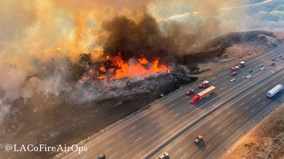 In this aerial photo released by the Los Angeles County Fire Department Air Operations traffic passes the Route fire, a brush wildfire off Interstate 5 north of Castaic, Calif., on Saturday, Sept. 11, 2021. (Los Angeles County Fire Air Operations via AP)