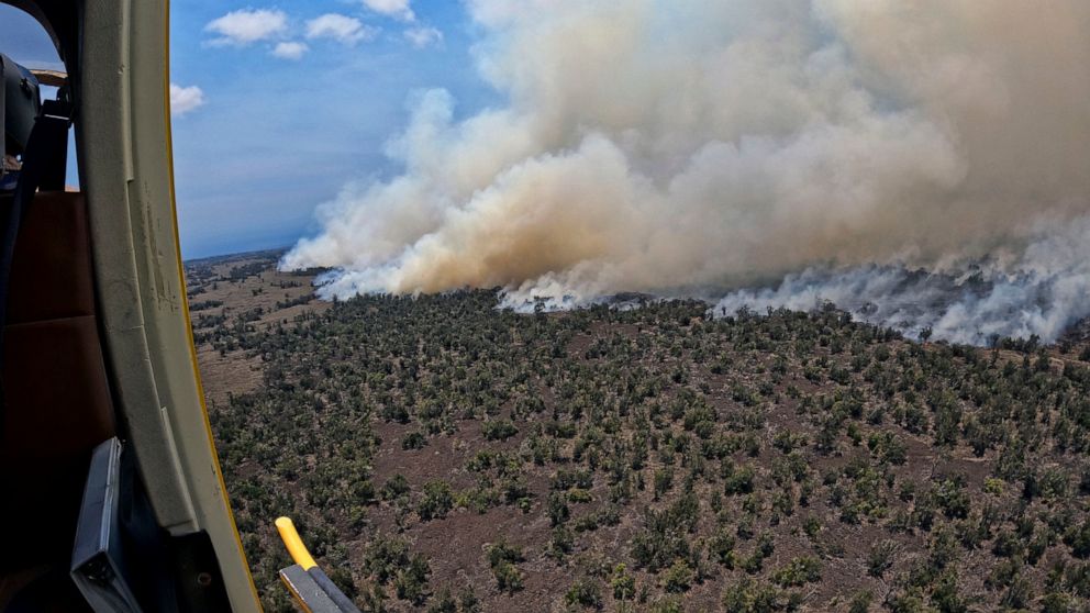 This photo provided by the Hawaii Department of Land and Natural Resources shows a large wildfire in a rural area of Hawaii's Big Island that is not threatening any homes, but high winds and extremely dry conditions are making it difficult for crews 