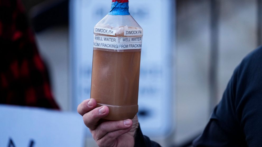 Craig Stevens holds a bottle of brown water as he speaks with members of the media outside the Susquehanna County Courthouse in Montrose, Pa., Tuesday, Nov. 29, 2022. Pennsylvania's most active gas driller has pleaded no contest to criminal environme