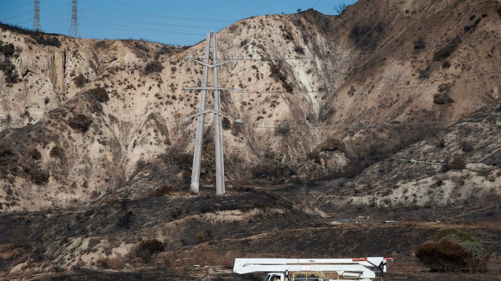 FILE - In this Oct. 15, 2019, file photo, SoCal Edison trucks arrive at the site of a transformer tower in Sylmar, Calif., suspected of being responsible for starting the Saddleridge fire. Southern California Edison will pay $2.2 billion to settle in