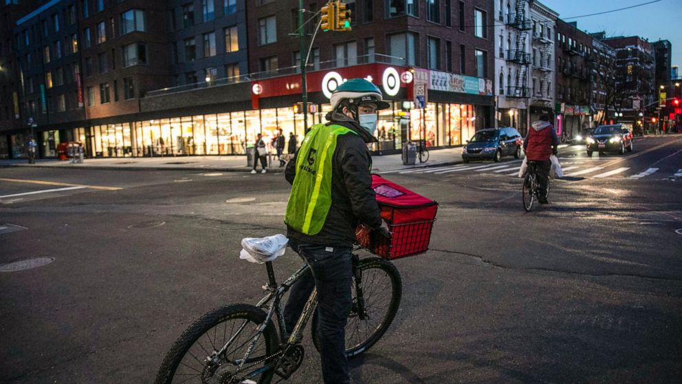 FILE - A cyclist delivering food stops at an intersection in the East Village neighborhood of New York, on Thursday, March 26, 2020. Food delivery workers and other app workers in New York City are pressing for protections including better wages, hea