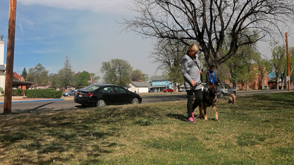 Liz Birmingham, 66, trains her dog Ciel at a class outside the Carnegie Library in Las Vegas, N.M., on Saturday, May 7, 2022. She said living in the city unnerving, as smoke and fire fluctuate with the winds, and some neighborhoods have been under ev