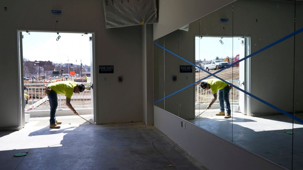 FILE - In this Monday, March 22, 2021 file photo, a construction worker is reflected in a wall mirror at Polar Park, Worcester Red Sox's Triple-A baseball stadium, in Worcester, Mass., where preparations are ongoing for the club's opening day in May.