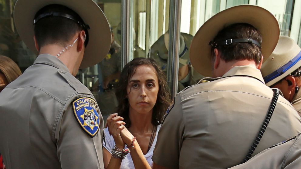 California Highway Patrol officers take into custody an opponent of recently passed legislation to tighten the rules on giving exemptions for vaccinations, after she cabled herself to the doors of the state Capitol in Sacramento, Calif., Monday, Sept