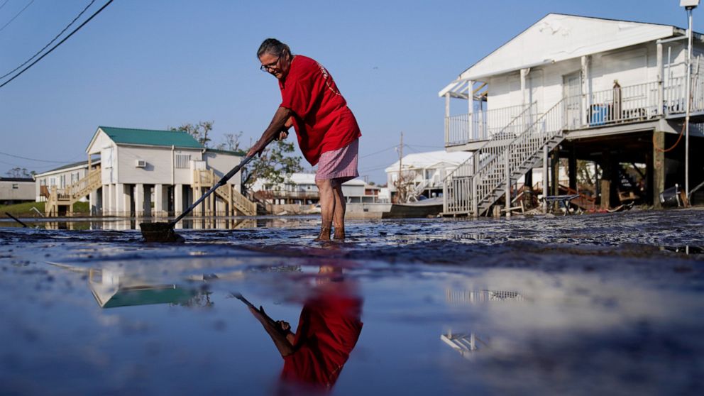 Cindy Rojas cleans mud and floodwater from her driveway in the aftermath of Hurricane Ida, Sunday, Sept. 5, 2021, in Lafitte, La. (AP Photo/John Locher)