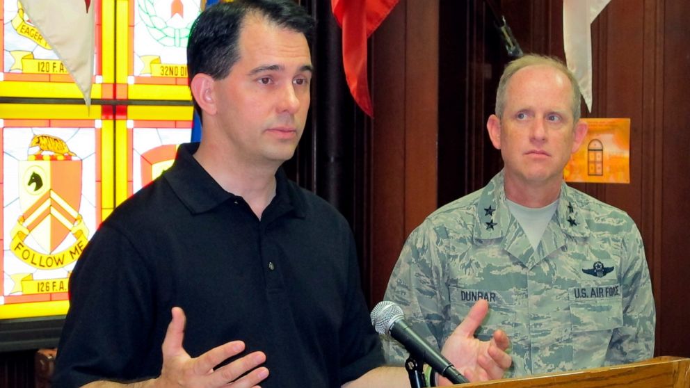 FILE - In this Sept. 7, 201 file photo, Wisconsin Army National Guard Maj. Gen. Don Dunbar, right, looks on as then Wisconsin Gov. Scott Walker talks to reporters in Milwaukee. Federal investigators plan to brief the Wisconsin National Guard's top co