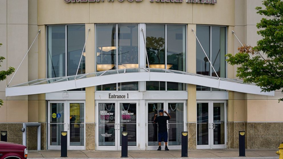 A customer checks a door on the closed Greenwood Park Mall in Greenwood, Ind., Monday, July 18, 2022. The mall was closed Monday after police say three people were fatally shot and two were injured, including a 12-year-old girl, after a man with a ri