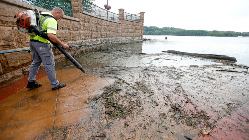 In this Wednesday, June 12, 2019 photo, Matt Cooper, with the City of Dubuque, cleans off an area of American Trust River's Edge Plaza in Dubuque, Iowa, after high water levels of the Mississippi River left large amounts of debris and mud. (Dave Kett