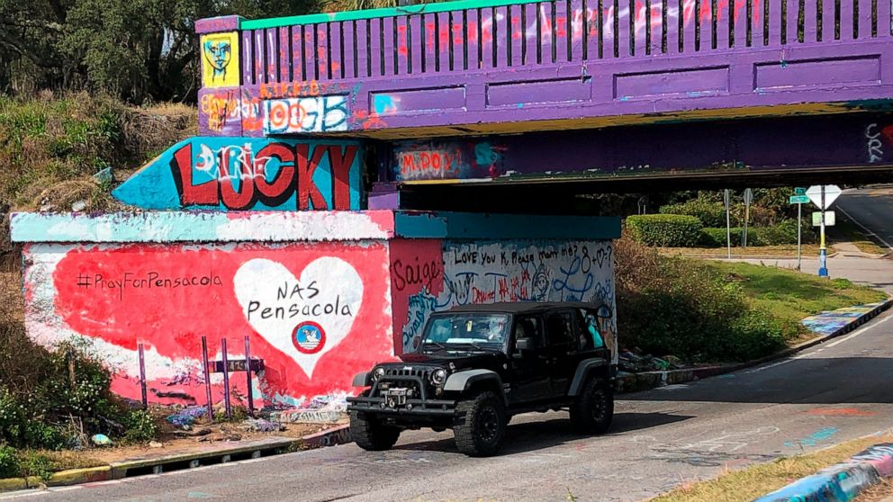 A vehicle drives by a tribute to victims of the Naval Air Station Pensacola that was freshly painted on what’s known as Graffiti Bridge in downtown Pensacola, Fla., on Saturday, Dec. 7, 2019. A US official says the Saudi student who fatally shot thre