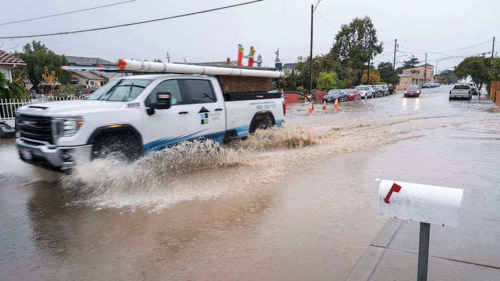 A truck drives through a flooded intersection of E Bolivar Street in Salinas, Calif., Tuesday, Dec. 27, 2022. The first in a week of storms brought gusty winds, rain and snow to California on Tuesday, starting in the north and spreading southward. (A