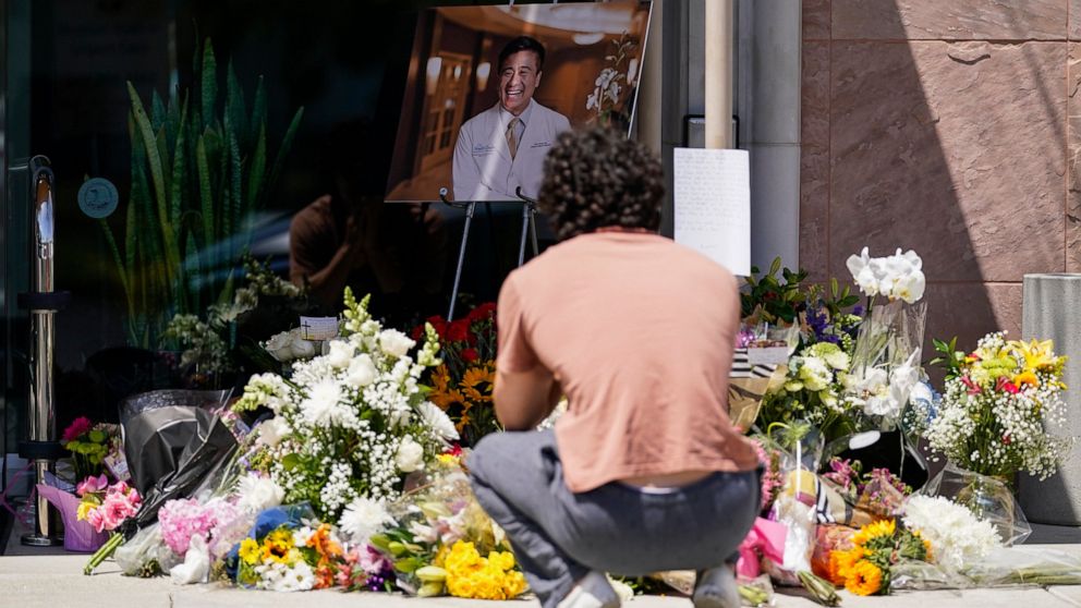 Gabe Kipers, a neighbor of Dr. John Cheng, kneels at a memorial for him outside his office building on Tuesday, May 17, 2022, in Aliso Viejo, Calif. Cheng, 52, was killed in Sunday's shooting at Geneva Presbyterian Church. (AP Photo/Ashley Landis)