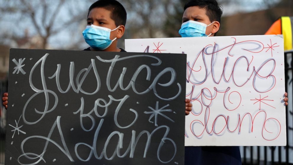 Jacob Perea, 7, left and Juan Perea, 9 holds signs on Tuesday, April 6, 2021, as they attend a press conference following the death of 13-year-old Adam Toledo, who was shot by a Chicago Police officer at about 2 a.m. on March 29 in an alley west of t