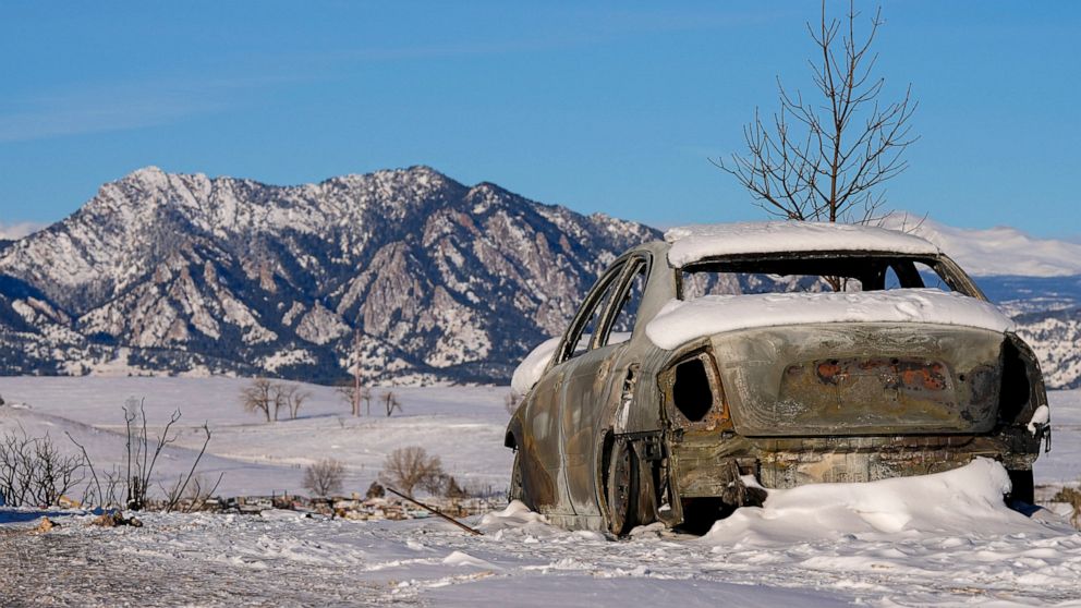 Snow covers the burned remains of a car after wildfires ravaged the area Sunday, Jan. 2, 2022, in Superior, Colo. Investigators are still trying to determine what sparked a massive fire in a suburban area near Denver that burned neighborhoods to the 