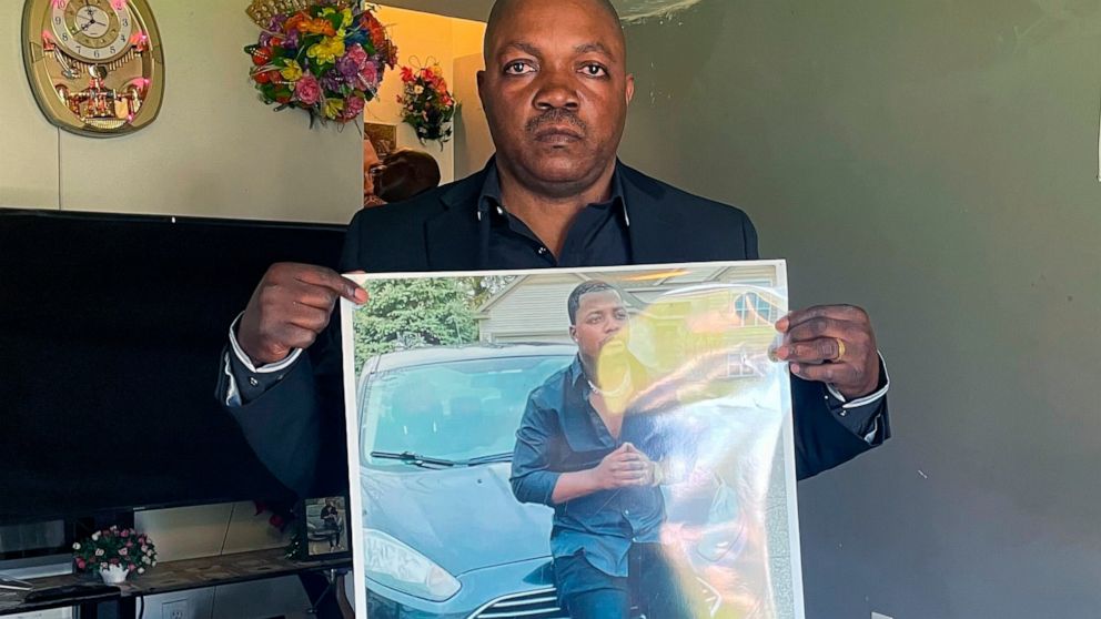 Peter Lyoya holds up a picture of his son Patrick Lyoya, 26, in his home in Lansing, Mich., April 14, 2022. Patrick was face-down on the ground when he was fatally shot in the head by a Grand Rapids Police officer after resisting arrest on April 4, 2