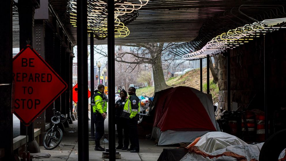 In this March 3, 2020 photo released by the University of Maryland via the Howard Center for Investigative Journalism, Washington, D.C., officials confer under a railroad overpass on L Street NE, about eight blocks from the U.S. Capitol, before garba