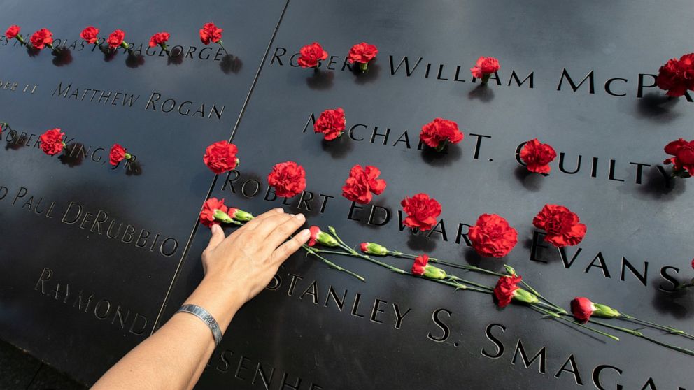Norma Molina, of San Antonio, Texas, leaves flowers by the names of firefighters from Engine 33 at the September 11 Memorial, Monday, Sept. 9, 2019, in New York. Her boyfriend Robert Edward Evans, a member of Engine 33, was killed in the north tower 