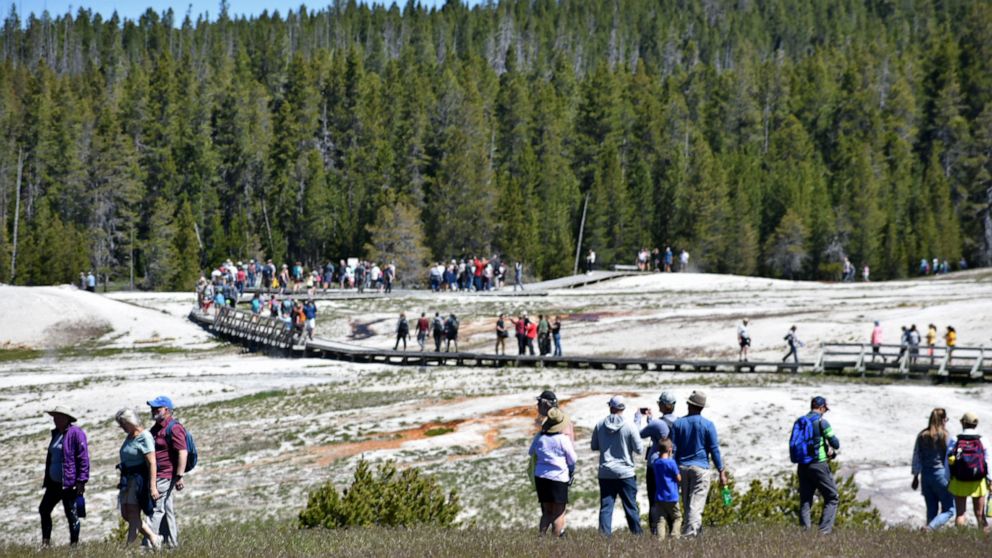 Tourists are see along a boardwalk in Upper Geyser Basin, Wednesday, June 22, 2022, in Yellowstone National Park, Wyo. Only the southern half of the park is open while repairs to extensive flood damage are made in the northern half. (AP Photo/Matthew