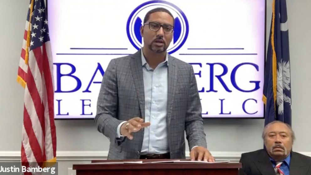 In this screen grab from video provided by Bamberg Law, LLC, attorney Justin Bamberg, standing, speaks at a news conference as plaintiff Jethro DeVane, seated at right, listens, Tuesday, Dec. 22, 2020, in Orangeburg, S.C. DeVane was embarrassed and f