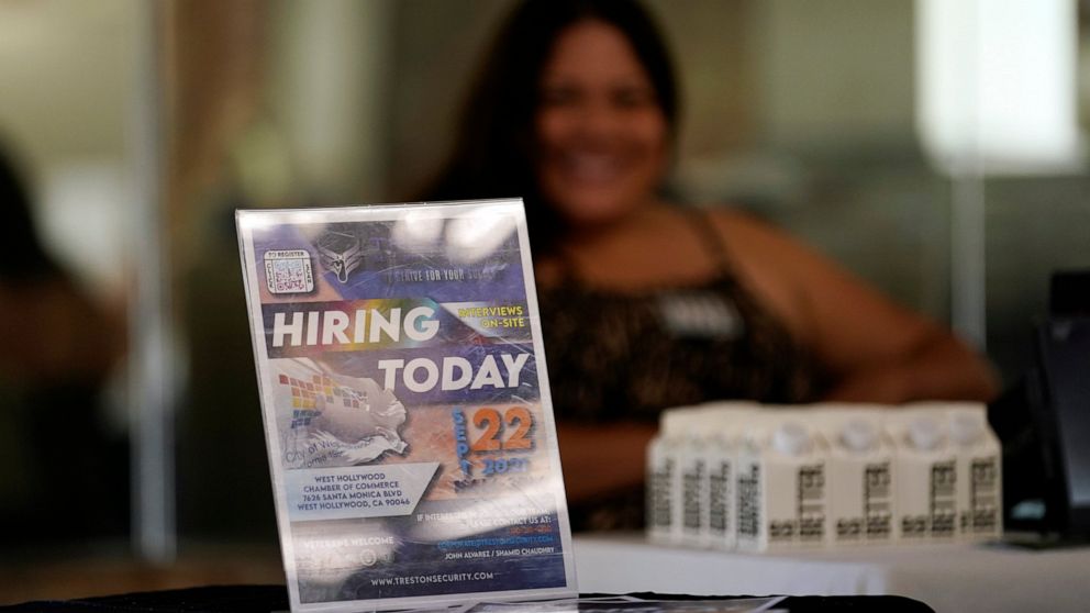 FILE - In this Sept. 22, 2021 file photo, a hiring sign is placed at a booth for prospective employers during a job fair in the West Hollywood section of Los Angeles. U.S. job growth slowed sharply last month as the highly contagious delta variant di