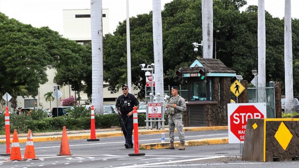 Security stand outside the main gate at Joint Base Pearl Harbor-Hickam, Wednesday, Dec. 4, 2019, in Hawaii. A shooting at Pearl Harbor naval shipyard in Hawaii left at least one person injured Wednesday, military and hospital officials said. (AP Phot
