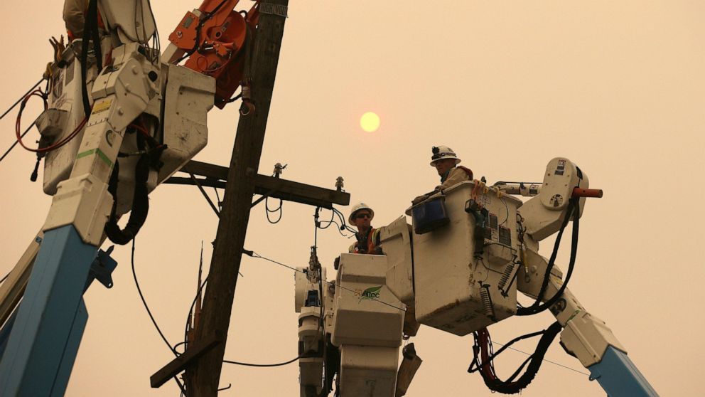 FILE - In this Nov. 9, 2018, file photo, Pacific Gas & Electric crews work to restore power lines in Paradise, Calif. Two years to the day after some of the deadliest wildfires tore through Northern California wine country, two of the state's largest