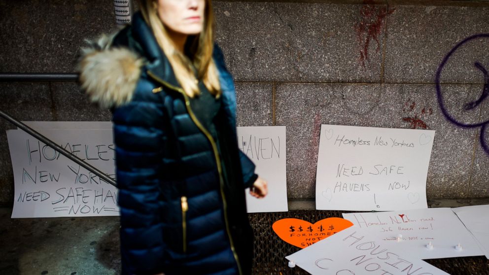 FILE - A pedestrian walks past by signs left as a memorial near the place where a homeless person was killed days earlier in lower Manhattan, Monday, March 14, 2022, in New York. The shootings and apprehension of the suspect, Gerald Brevard III, refo