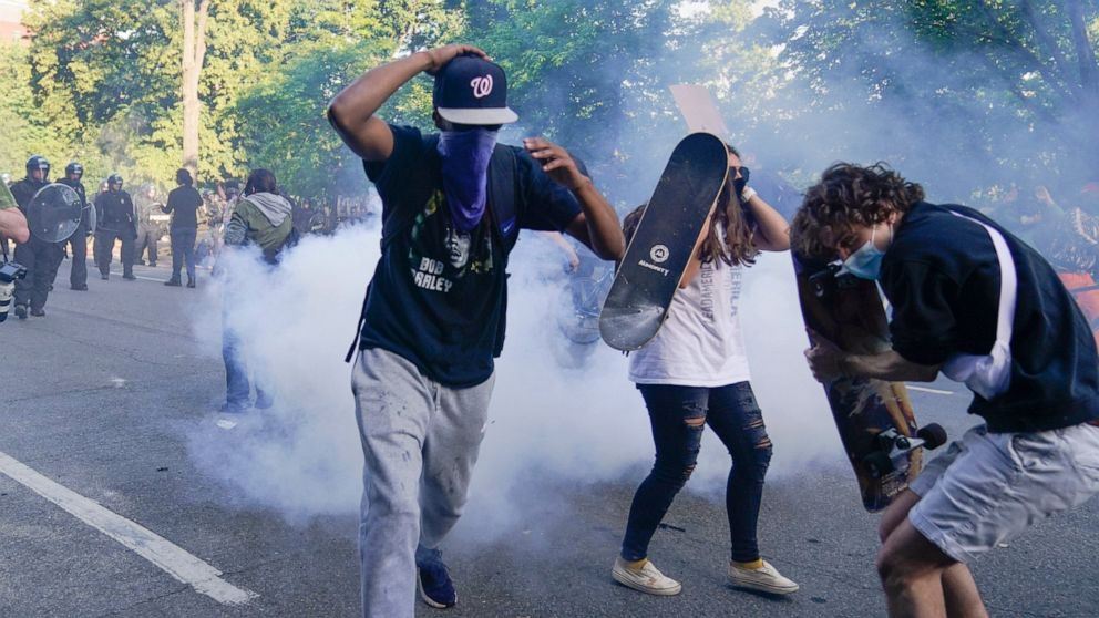 Demonstrators, who had gathered to protest the death of George Floyd, begin to run from tear gas used by police to clear the street near the White House in Washington, Monday, June 1, 2020. Floyd died after being restrained by Minneapolis police offi